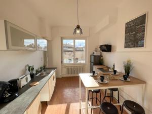 a kitchen with a sink and a counter with stools at Chambres privées -Private room- dans un spacieux appartement - 100m2 centre proche gare in Mulhouse