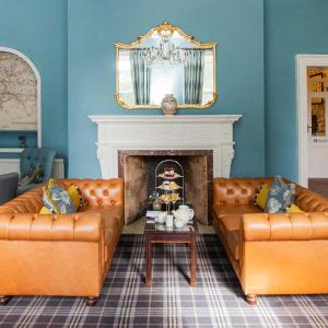 a living room with two leather couches and a fireplace at Stratton House Hotel & Spa in Cirencester