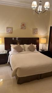 a bedroom with a large bed with two tables and a chandelier at Al Gosaibi Hotel-Villa in Al Khobar
