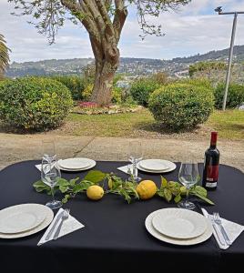 a black table with plates and glasses and a bottle of wine at Hostal San Cristobal - Pontedeume in Puentedeume