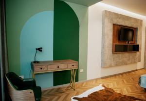 a room with a green wall with a desk and a television at Centropolis Apartments in Shkodër