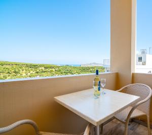 una mesa con una botella y dos vasos en el balcón en Orestis Hotel Sea View Apartments, en Stalós