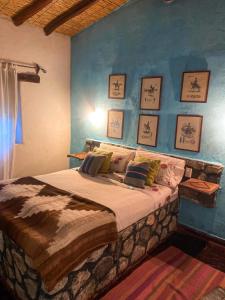 1 dormitorio con 1 cama grande y pared azul en Casa de Campo La Paya en Cachí