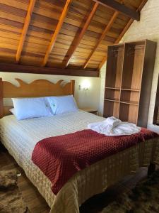 a bedroom with a bed in a room with wooden ceilings at Chales Elliotti in Monte Verde