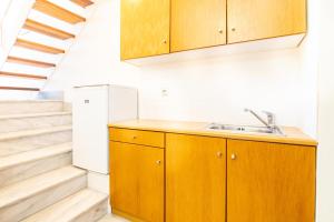 a kitchen with wooden cabinets and a staircase at Orestis Hotel Sea View Apartments in Stalos