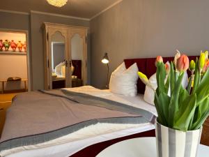 a bedroom with a bed with a vase of flowers on a table at Gästezimmer in herrschaftlicher Villa in Krakow am See