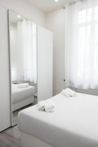 LA CORTE LUXURY APARTMENT في ميلانو: غرفة بيضاء بسريرين ومرآة