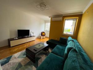 sala de estar con sofá verde y TV en Apartman Ruby, en Doboj
