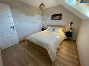 Gites La Ville Pain في كانكال: غرفة نوم بسرير ذو شراشف بيضاء وارضيات خشبية