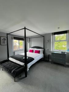 a bedroom with a black canopy bed with pink pillows at Gordons in Cheddar