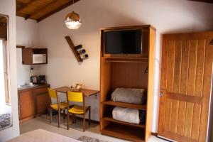 a room with a desk and a table with a television at Suites Hencke Haus in Canela
