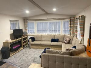 a living room with a couch and a flat screen tv at The Cedar lake Southview Skegness in Lincolnshire