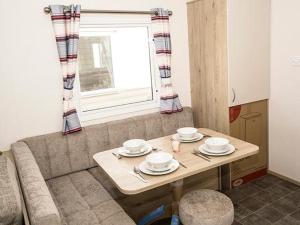 een woonkamer met een tafel en een bank bij The Cedar lake Southview Skegness in Lincolnshire
