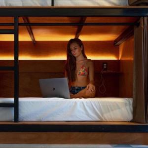 kobieta siedząca na łóżku z laptopem w obiekcie Cancun Hostel w mieście Cancún