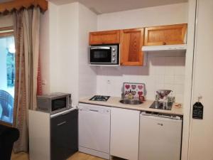 a small kitchen with a sink and a microwave at Le repère des écureuils in Samoëns