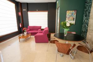 sala de estar con mesa y sofá rosa en Hotel Bracamonte, en Peñaranda de Bracamonte