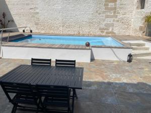 una mesa y sillas junto a una piscina en Maison chaleureuse avec piscine et parking, en Saint-Gelais