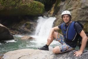 a man sitting on a rock in front of a waterfall at Enjoy Colombia Hostel in Villavicencio