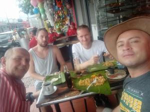 un grupo de hombres sentados en una mesa con comida en Enjoy Colombia Hostel en Villavicencio