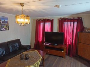 sala de estar con cortinas rojas y TV de pantalla plana en Norway Stabben Tour, en Tustna