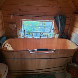 bañera de madera con fregadero y ventana en Cabane des lutins - Belle Fleur, en Saint-Nabord