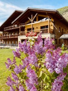 a building with purple flowers in front of it at Hotel L'Artisin in Limone Piemonte