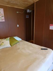 una cama con mando a distancia sentada encima de ella en Casa Alojamiento, en Punta Arenas