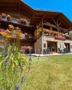 a building with a balcony with flowers in the yard at Hotel L'Artisin in Limone Piemonte