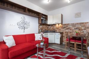 a living room with a red couch and a kitchen at Tatry Apartman, PRIMO, Starý Smokovec, Vysoké Tatry in Starý Smokovec