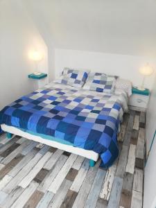 1 cama azul y blanca en una habitación con 2 lámparas en Maison bord de mer, en Penmarch