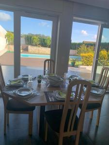 einen Esstisch mit Stühlen und einen Tisch mit Tellern und Geschirr in der Unterkunft Casa Beiriz in Póvoa de Varzim