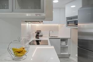 a white kitchen with bananas in a bowl on the counter at Varandas do Lido I by An Island Apart in Funchal