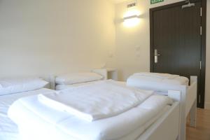 Habitación con 3 camas y sábanas blancas. en ATERPE KANPEZU HOSTEL, en Santa Cruz de Campezo