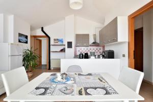 une cuisine et une salle à manger avec une table et des chaises blanches dans l'établissement Casa Vacanze Mameli, à Bari Sardo