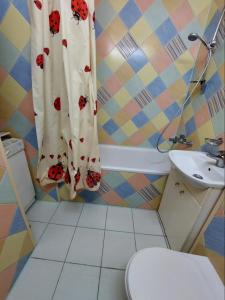 a bathroom with a toilet and a shower curtain with roses at Apartment on Voli Avenue 21 in Lutsk