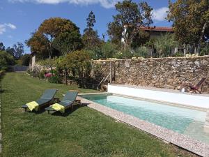 een zwembad met 2 stoelen en een stenen muur bij Moleiro's Country House in Esposende