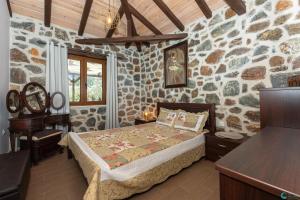 um quarto com uma cama numa parede de pedra em Eleni's Stone House em Skala Potamias