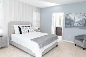 a white bedroom with a bed and a chair at Marvelous Villa, South facing pool and hot tub, themed bedrooms near Disney in Davenport +55 photos