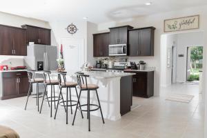 a kitchen with brown cabinets and a counter with bar stools at Marvelous Villa, South facing pool and hot tub, themed bedrooms near Disney in Davenport