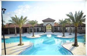 a pool with palm trees in front of a building at Marvelous Villa, South facing pool and hot tub, themed bedrooms near Disney in Davenport