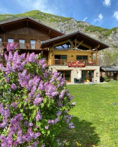 a log cabin with purple flowers in front of it at Hotel L'Artisin in Limone Piemonte