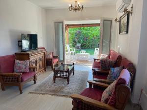 un soggiorno con divani, sedie e TV di Cheerful fully furnished 3 bedroom villa in North Coast a Dawwār Abū Maḩrūs