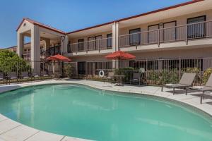a pool in front of a hotel with chairs and umbrellas at Best Western Lindale Inn in Lindale