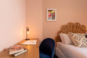 a room with a desk with a bed and a table with a lamp at Roamer St Kilda - formerly Selina St Kilda Melbourne in Melbourne