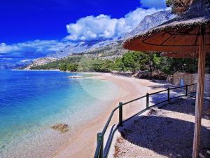 a beach with an umbrella next to the water at Apartments Villa Katarina in Makarska