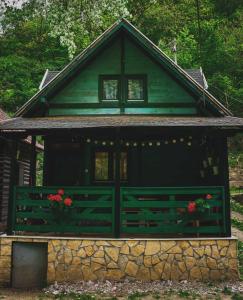 una casa verde con una valla y flores delante en Vikendica,, Tadic,, Ovčar Banja, en Ovčar Banja