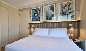a bedroom with a white bed with three pictures on the wall at Apart Hotel Las Terrazas Suite in Chillán