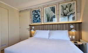 a bedroom with a white bed with pictures on the wall at Apart Hotel Las Terrazas Suite in Chillán