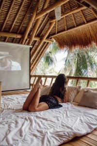 Eine Frau auf einem Bett in einem strohgedeckten Zimmer in der Unterkunft La royale Romantic Bamboo Villas in Klungkung