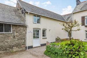 a cottage with a white door and a stone building at Stable Cottage in Ilfracombe